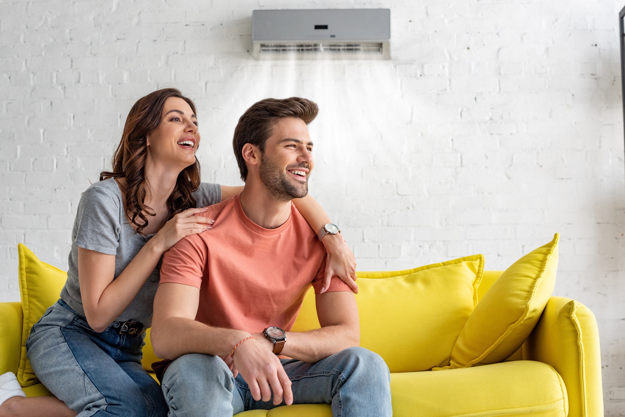 Smiling Couple Enjoying Comfort Under Home Air Conditioner